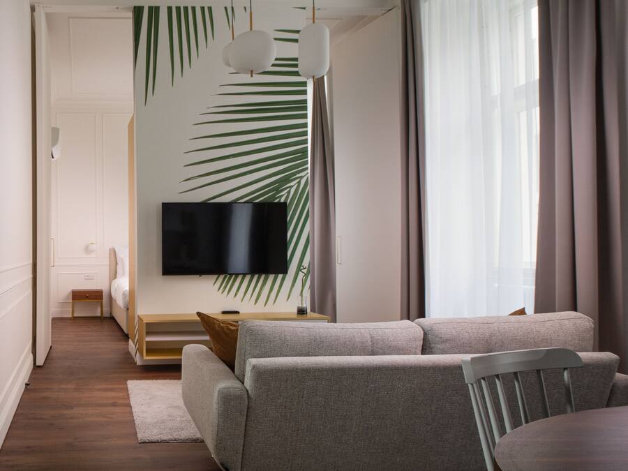 Una sala moderna con un sofá, una mesa de comedor y un televisor de pantalla plana montado en la pared.