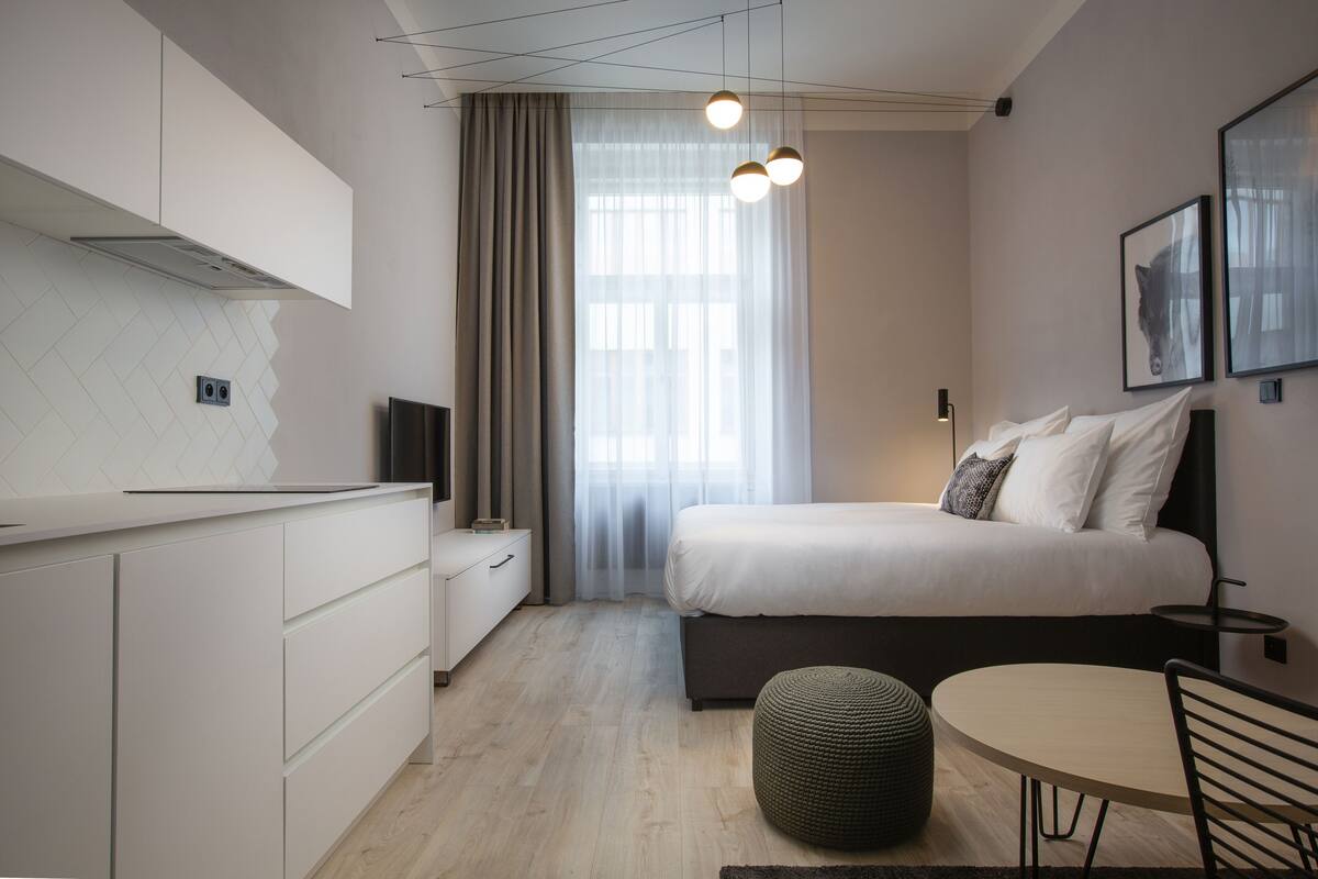 A modern bedroom with a bed, bedside table, and a small round table.