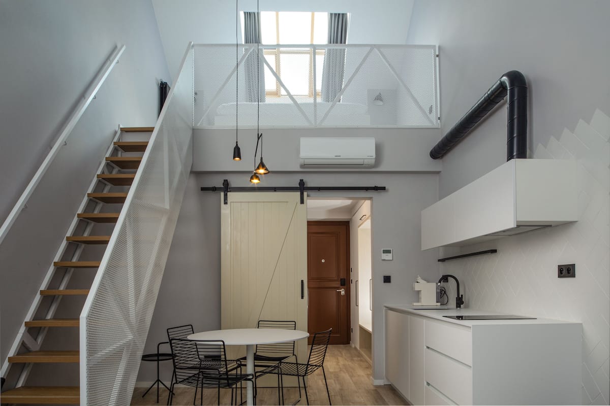 A modern kitchen with a white countertop, a sink, and a window above the stove.
