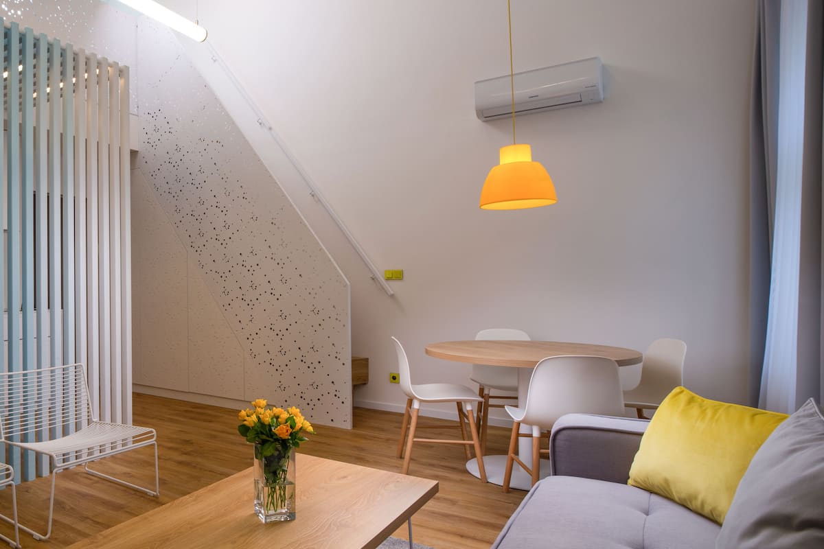 A modern living space with a dining area, a sofa, and a table with a vase of flowers.