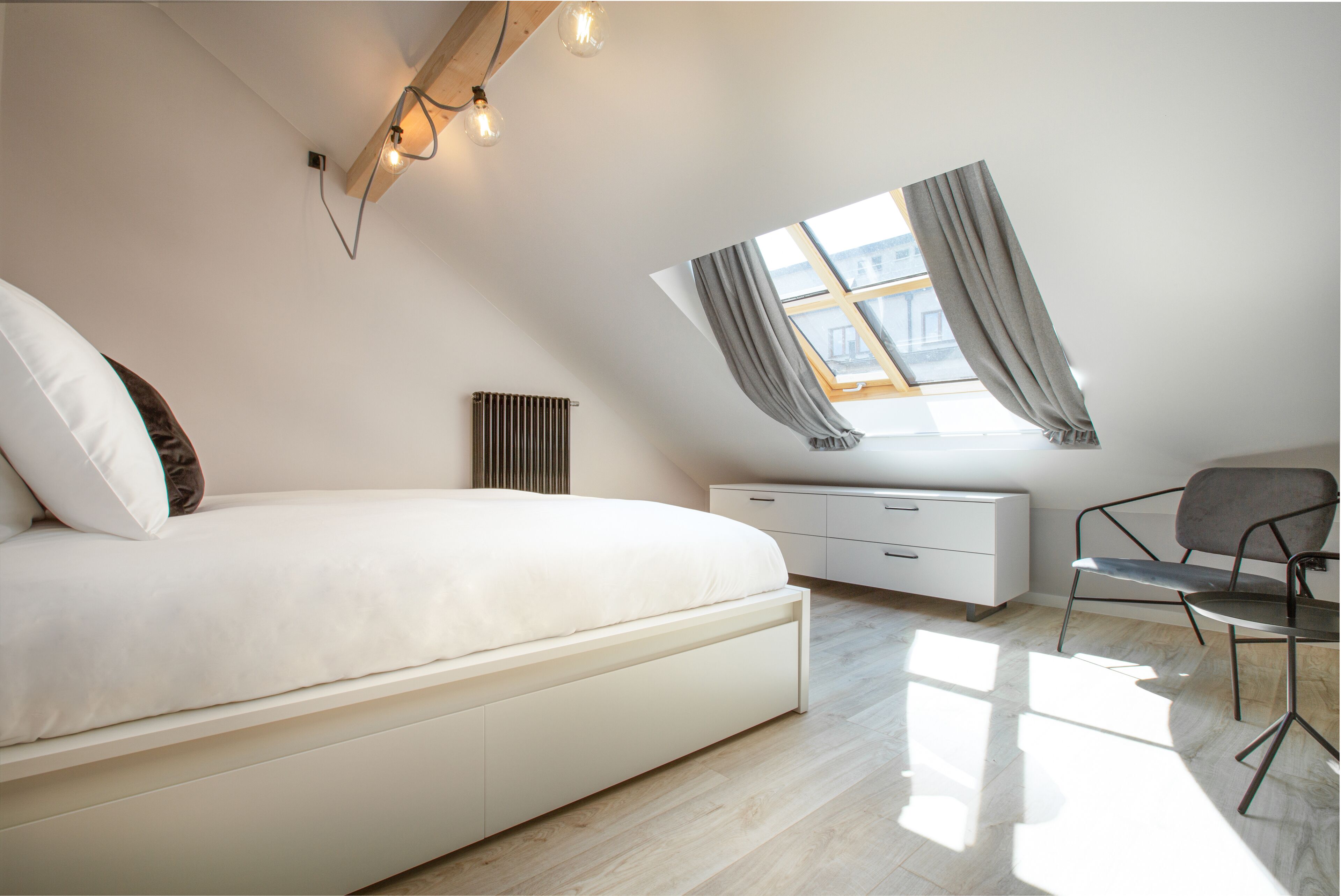 Un dormitorio moderno con cama, escritorio, silla y tragaluz.