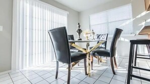 Un coin repas avec une table ronde, des chaises noires et un lustre.