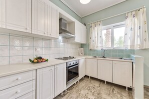Una cocina con armarios blancos, una estufa y un lavamanos.