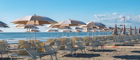 Aan een privéstrand, wit zand, ligstoelen, beachvolleybal