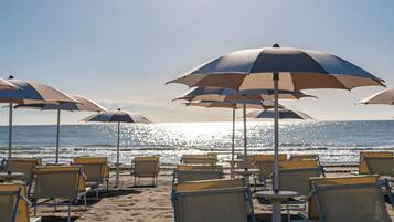 Een privéstrand, wit zand, ligstoelen aan het strand, beachvolleybal