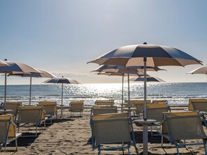 Een privéstrand, wit zand, ligstoelen aan het strand, beachvolleybal