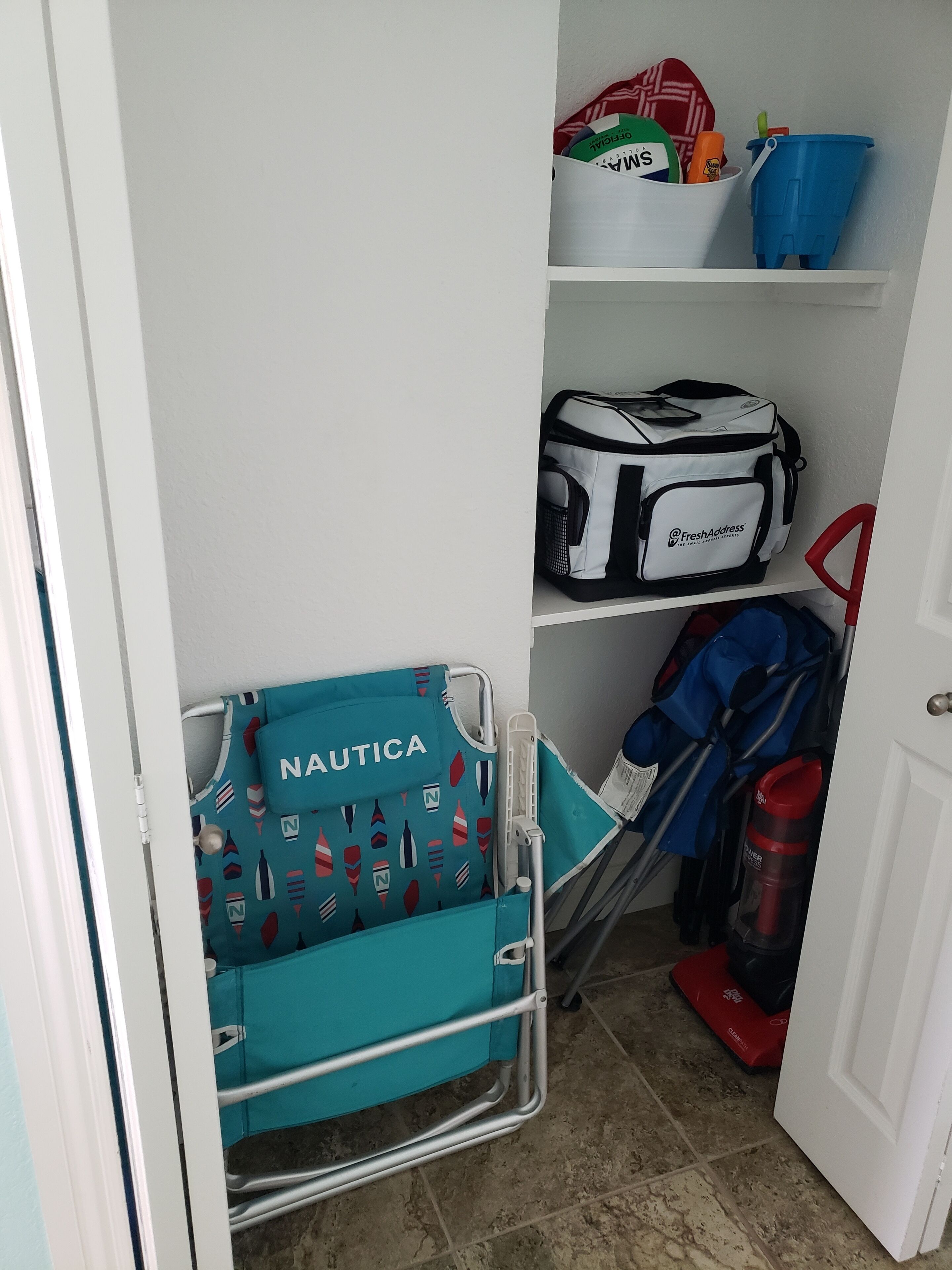 Ein Lagerbereich mit einem Wagen, der mit „NAUTICA“ beschriftet ist, einer weißen Tasche mit „FreshAddress“-Branding und einem blauen Eimer.