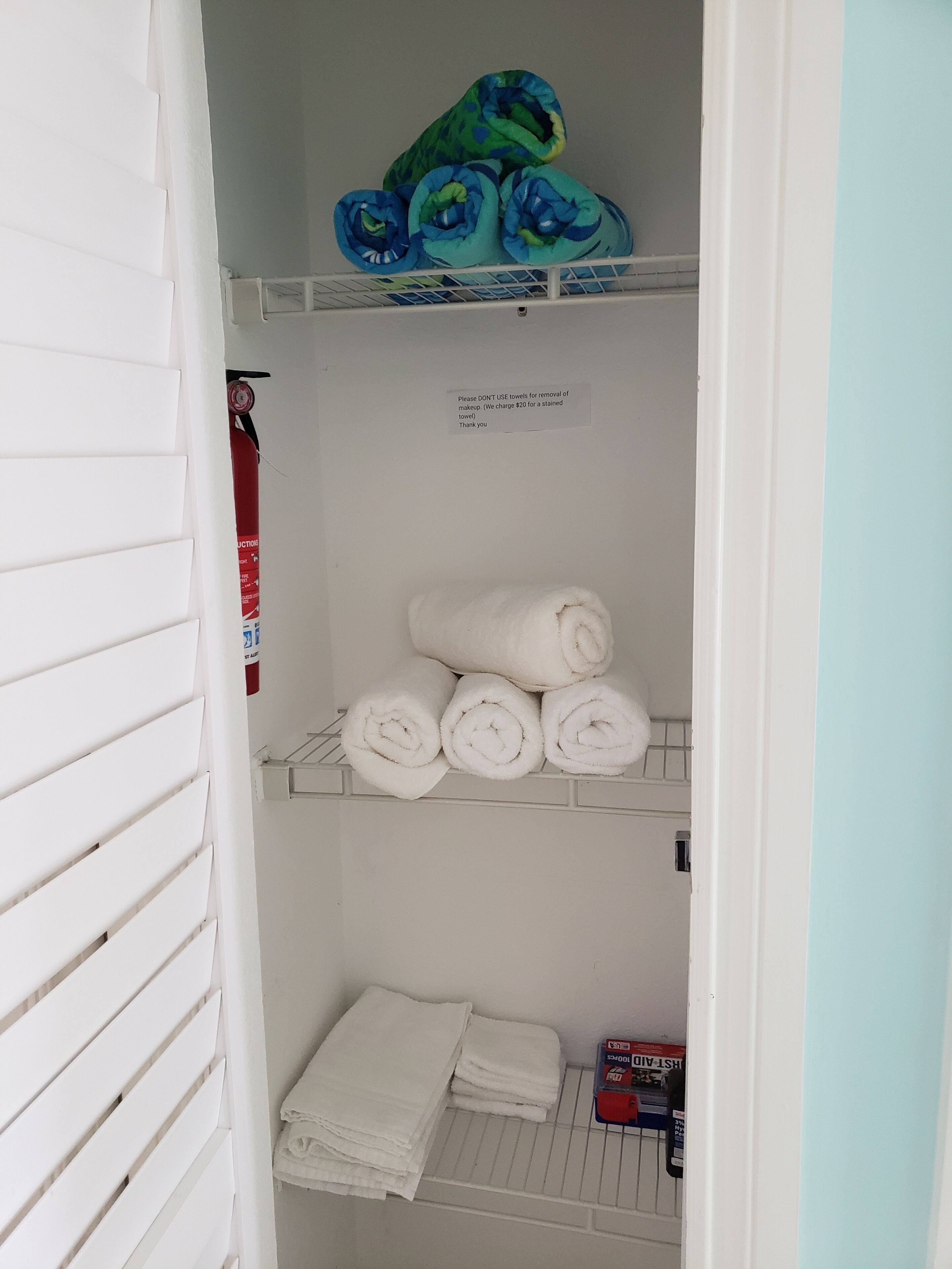 A storage area with shelves holding towels and a fire extinguisher.