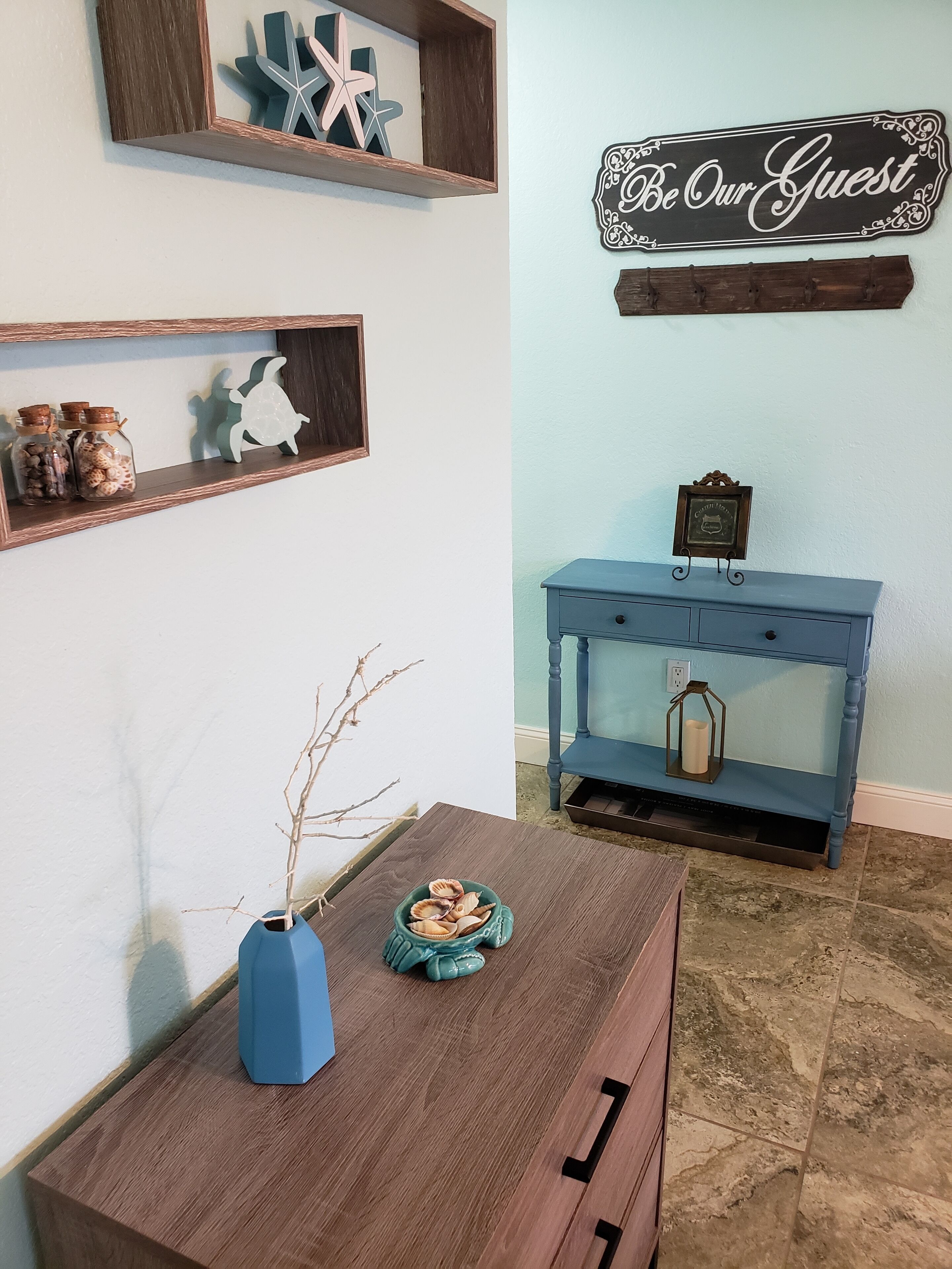 Una habitación con un aparador de madera, una consola azul y estantes con adornos.