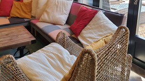 A modern living room with a sofa, wicker chairs, a small table, and a vintage radio.