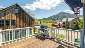 Una cabana de fusta amb terrassa, barbacoa i dipòsit de propà.
