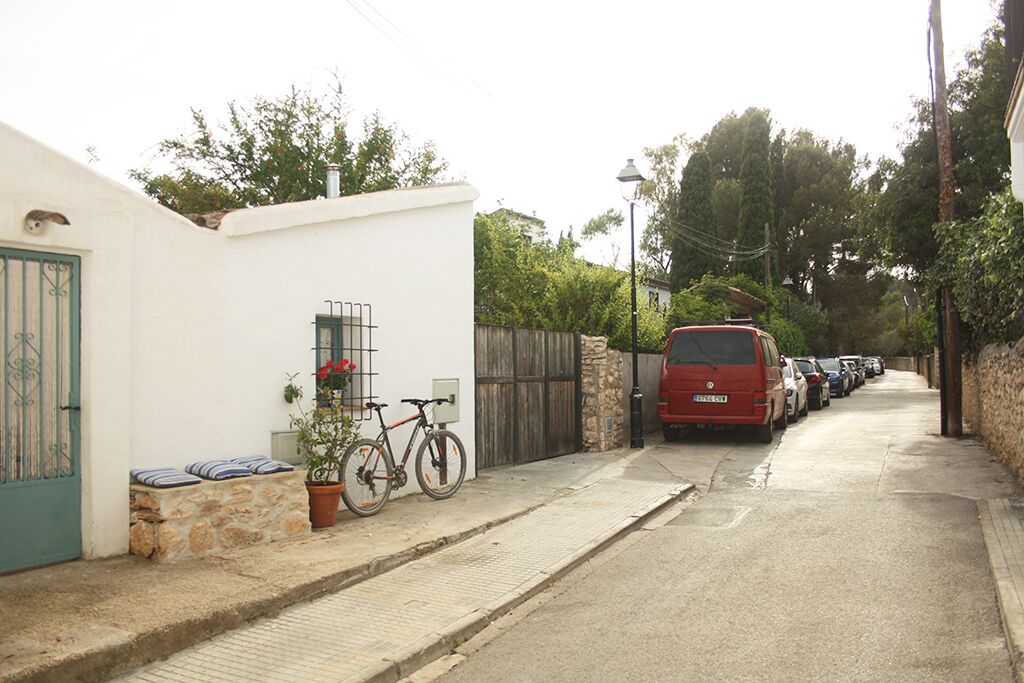 Una calle estrecha con coches aparcados y una bicicleta apoyada en una pared.