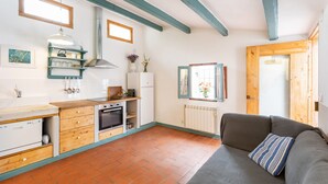 Une cuisine compacte dotée d’un four encastré, d’un réfrigérateur et d’un plan de travail en bois.