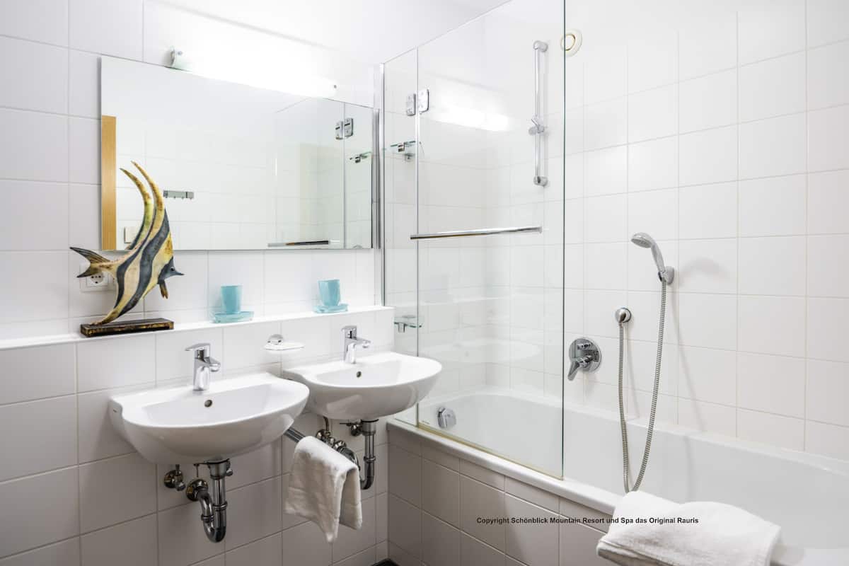 A modern bathroom with two sinks, a glass-enclosed shower, and a bathtub.