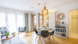 Een moderne woonkamer met een eethoek, houten vloeren en een boekenkast.