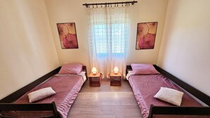 A small, well-lit bedroom with two single beds, each with a bedside table and lamp. - Sunflower House With a Pool and Large Garden (Omis)