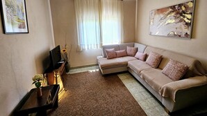 A living room with a sofa, a TV, a painting, and a window with curtains. - Sunflower House With a Pool and Large Garden (Omis)
