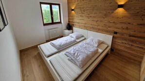 Une chambre avec deux lits simples, une fenêtre, un radiateur et un mur en bois doté d’un éclairage intégré.