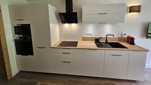 Une cuisine moderne dotée d’appareils électroménagers intégrés, d’un plan de travail en bois et de meubles de rangement blancs.