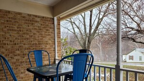 A covered patio with a brick wall, a glass table, and blue chairs. - Peaceful Single-Level Retreat, Near Harpers Ferry,  Easy Access + Prime Location (Harpers Ferry)