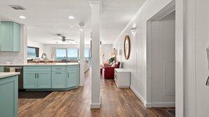 A modern kitchen with a central island, a dining area with a red sofa, and a view of the ocean. - Oceanfront Penthouse w/ Tons of Space and a Pool (Ocean City)