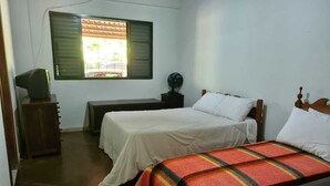 Un dormitorio con dos camas, un escritorio, una silla y una ventana con persianas.