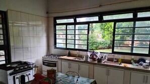 Una cocina con armarios blancos, estufa, horno y ventana con vistas al verdor.