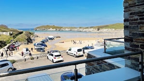 A beachside parking area with cars and a view of the beach and sea.