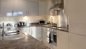 A modern kitchen with stainless steel appliances, a granite countertop, and white cabinetry.
