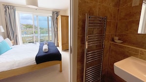 A hotel room with a bed, a towel, a shower area, and a view through the window.