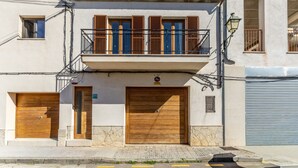 Een gebouw met een balkon, houten luiken en een garagepoort.