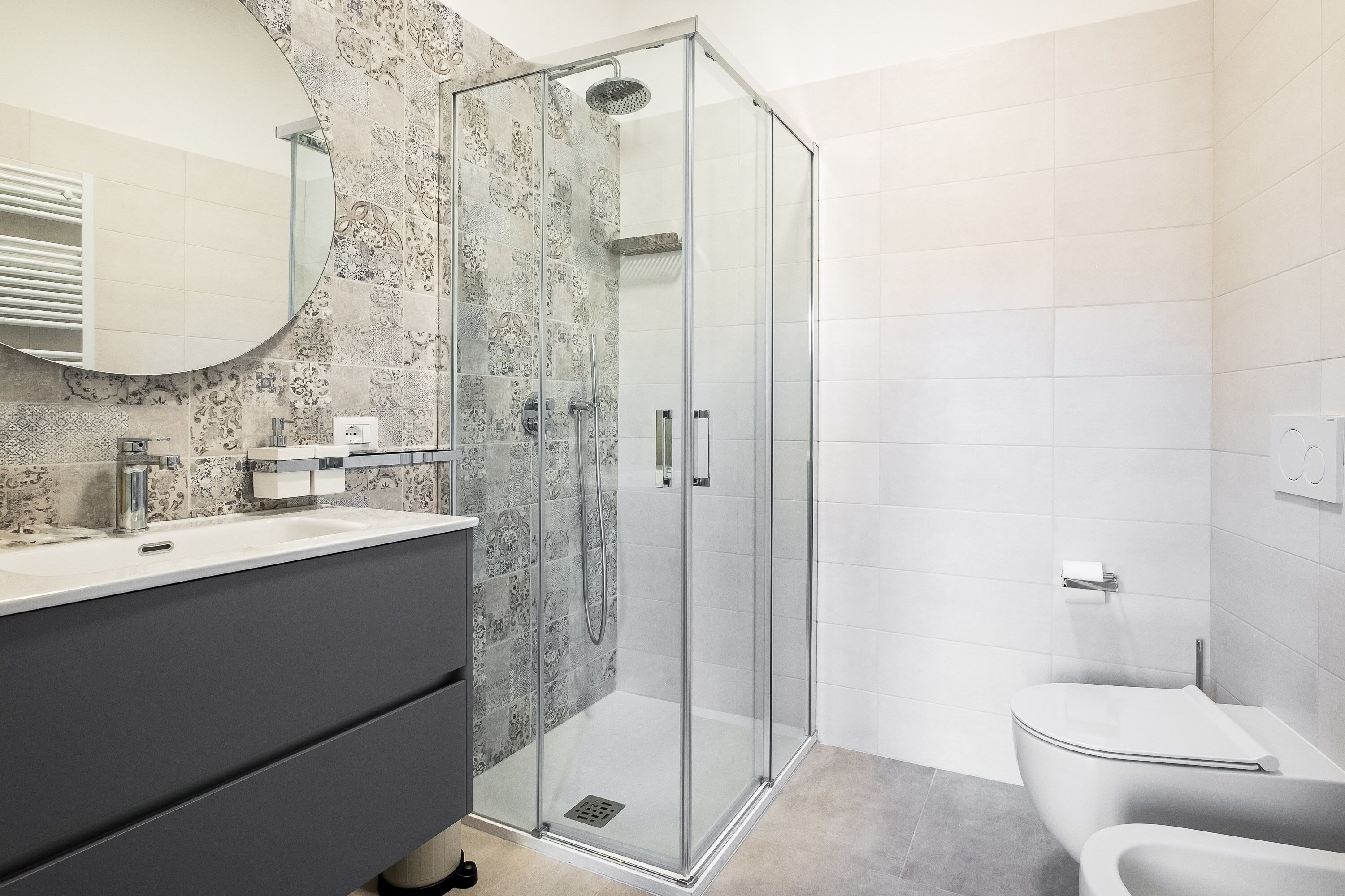 A modern bathroom with a glass-enclosed shower, a white toilet, and a vanity with a mirror.