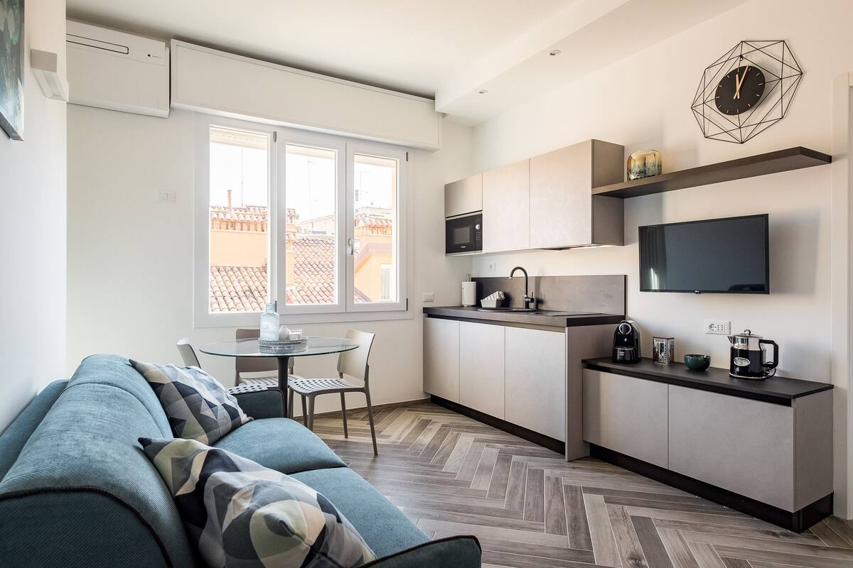 A modern kitchen with a built-in microwave, a coffee maker, and a flat-screen TV.