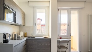 Una cucina moderna con forno a microonde integrato, macchina del caffè e lavello. Una finestra permette l'ingresso di luce naturale e offre vista all'esterno.