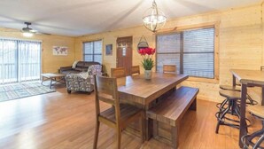 A spacious living area with a wooden floor, a dining table with benches, a sofa, and a chandelier. - Cabin Sleeps 12, Hot Tub, Movie Room, Game Room (Sevierville)