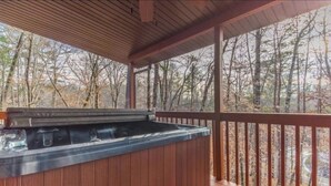 A hot tub on a wooden deck with a view of trees. - Cabin Sleeps 12, Hot Tub, Movie Room, Game Room (Sevierville)