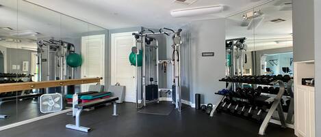 A gym with exercise equipment, mirrors, and a rack of dumbbells.