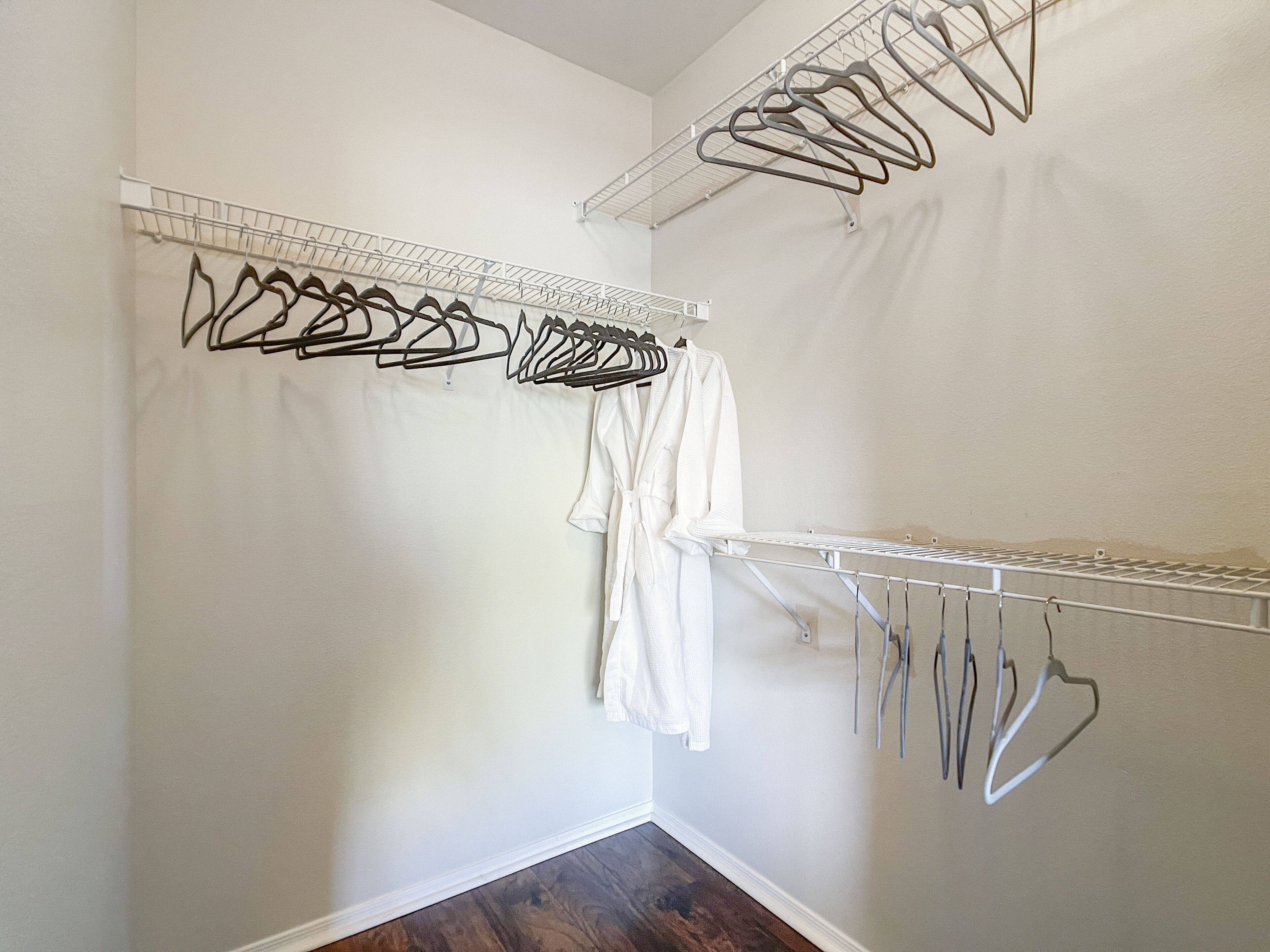 Um closet amplo com vários cabides de metal e um roupão branco pendurado em um suporte.