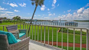 A balcony with wicker furniture and a view of a marina.