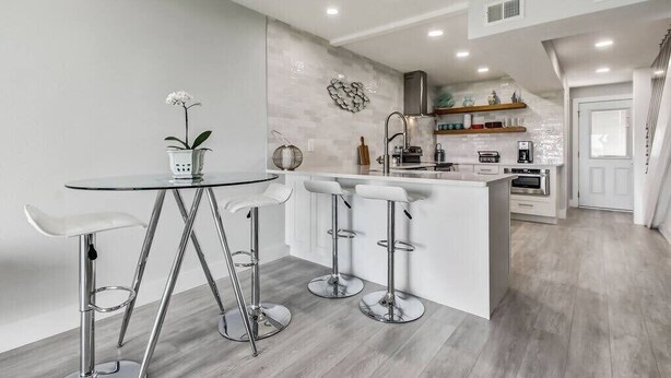 A modern kitchen with a central island, bar stools, and a round table.