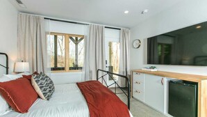 Ein modernes Schlafzimmer mit Bett, Nachttisch und großem Fenster.