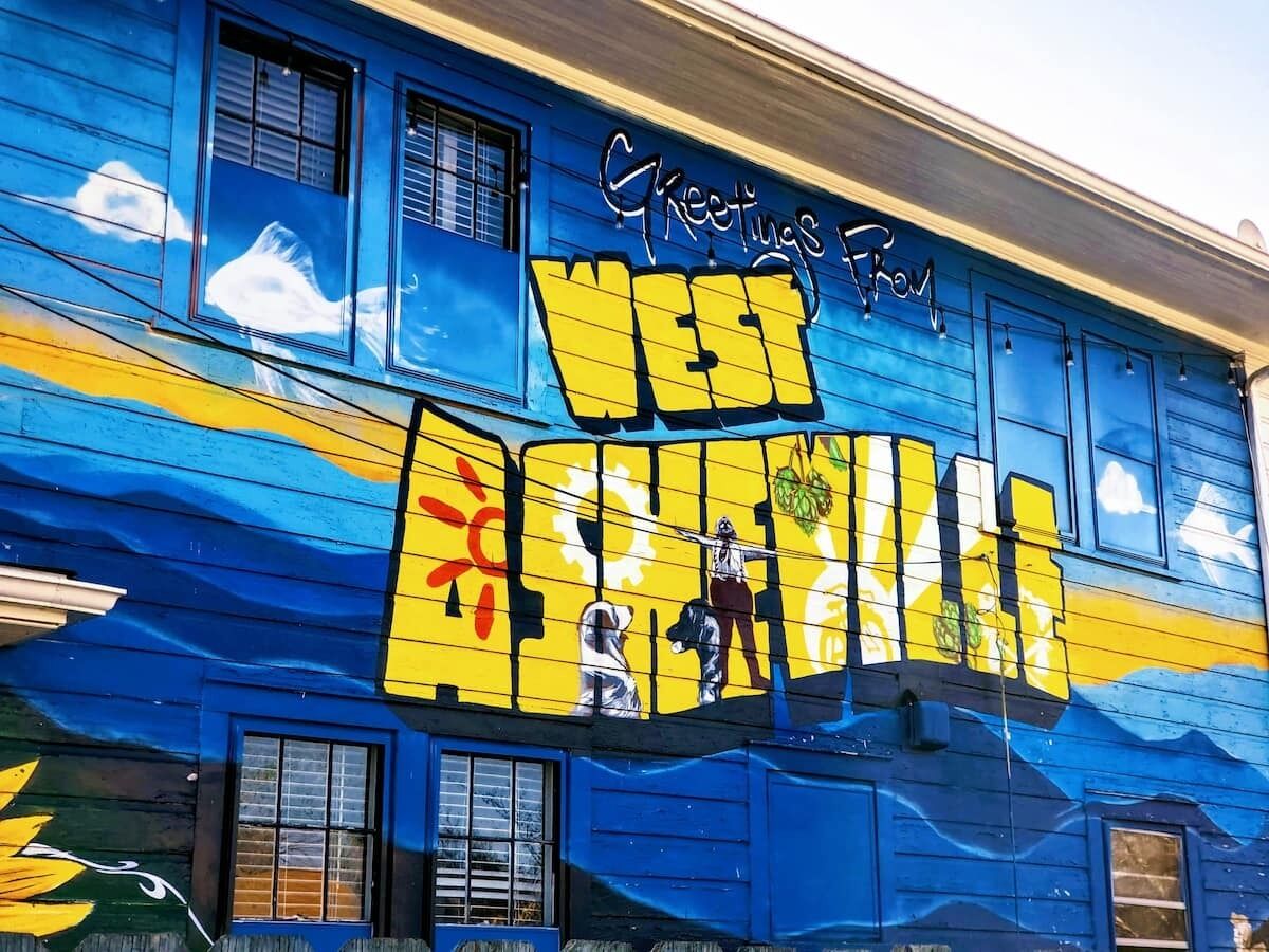 A building with a mural featuring a woman and a dog, and the text "Greetings From West Aquamarine."
