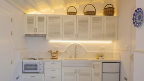 Una cucina con mobili bianchi, un forno a microonde, un lavandino e un frigorifero.