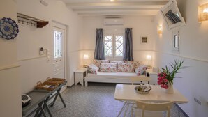 Una stanza accogliente con un letto, un tavolo con sedie, un piccolo tavolino con un cesto e una mensola a parete.