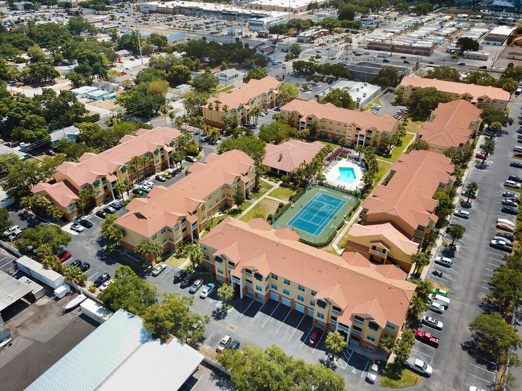 Ett flygbildsfoto av ett hotellkomplex med flera byggnader, en central innergård med en swimmingpool och en tennisbana.