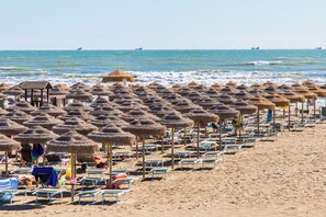 A beach with rows of sun loungers and thatched umbrellas. - Club Del Sole Rivaverde Easy Camping Village (Ravenna)