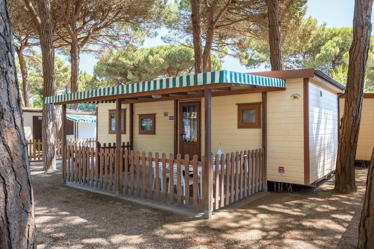Eine kleine, eingeschossige Holzhütte mit einem Holzzaun, einer Veranda und einer Tür mit Fenster.