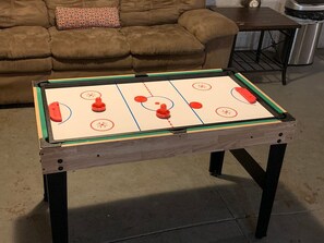 A foosball table in a room with a brown couch and a metal trash bin in the background. - Stunning Nashville Charm - Convenient to Downtown (Nashville)