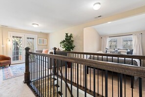 Une pièce spacieuse avec une grande fenêtre, un escalier et un coin salon confortable.