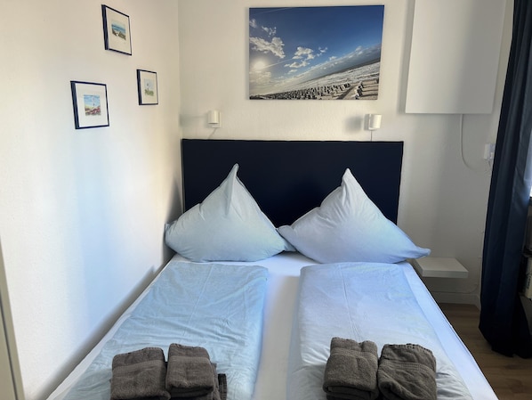 A twin room with two beds, each with a pillow and a folded towel. - Lüttjer Kiwitt - perfect location for short distances and relaxing days (Wangerooge)